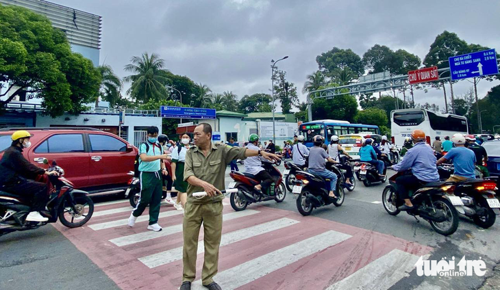 Ban An toàn giao thông TP.HCM chỉ khuyến cáo tốc độ 30km/h khu vực trường học, bệnh viện...- Ảnh 1. Trước cổng Trường THCS Hà Huy Tập (quận Bình Thạnh), xe cộ đi lại nườm nượp mỗi ngày. Vào giờ cao điểm, bảo vệ dân phố hoặc nhân viên trường phải có mặt cảnh báo dòng xe giảm tốc, nhường đường cho học sinh - Ảnh: THU DUNG